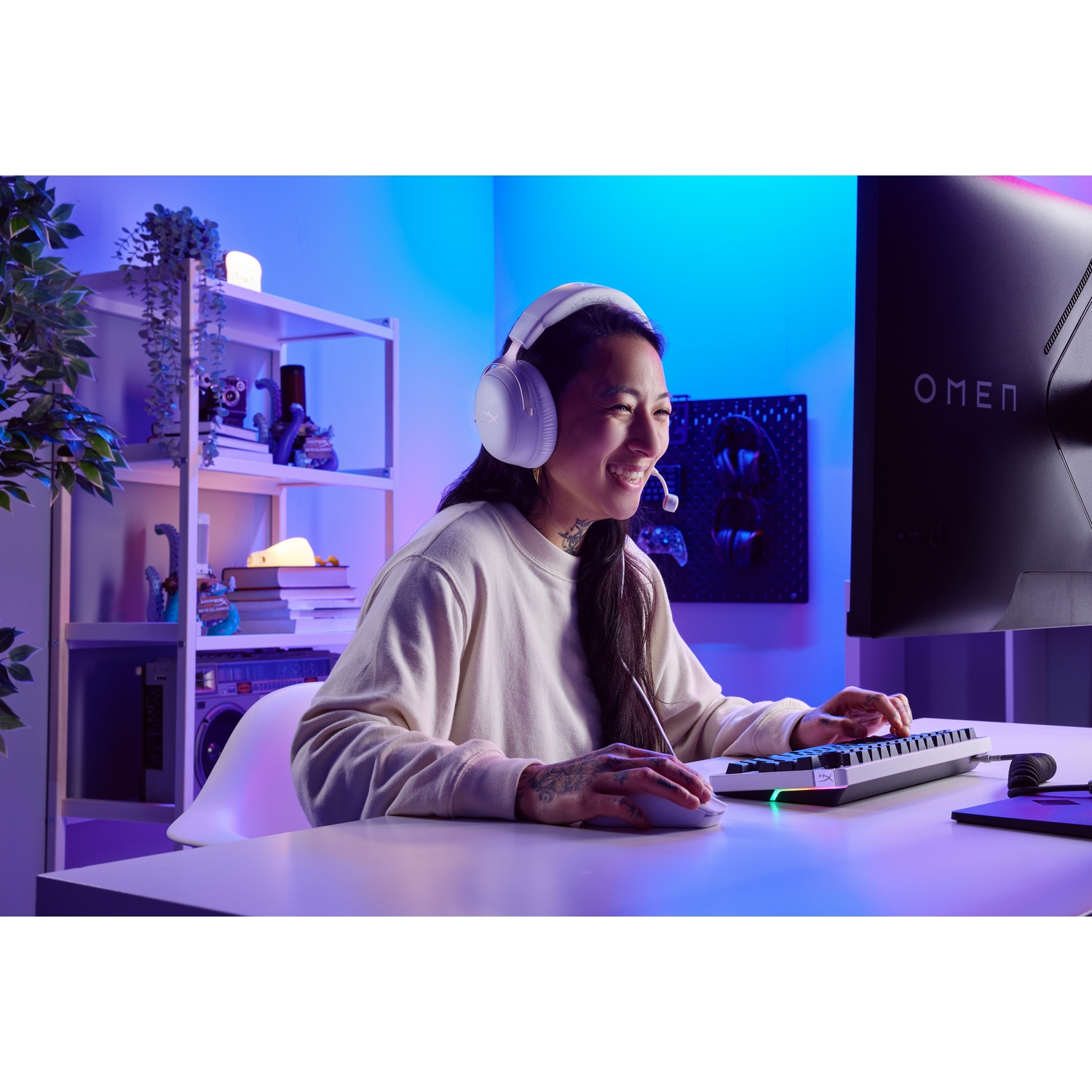 A woman with a headset smiles while using a keyboard and mouse. A computer monitor displays the word OMEN.