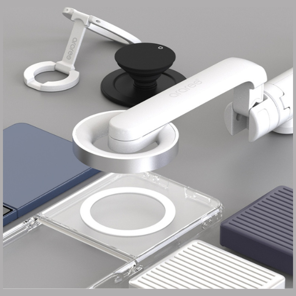 Różne akcesoria do telefonów, w tym pop socket, stojaki i etui, wszystko w kolorze białym i szarym, na szarej powierzchni.