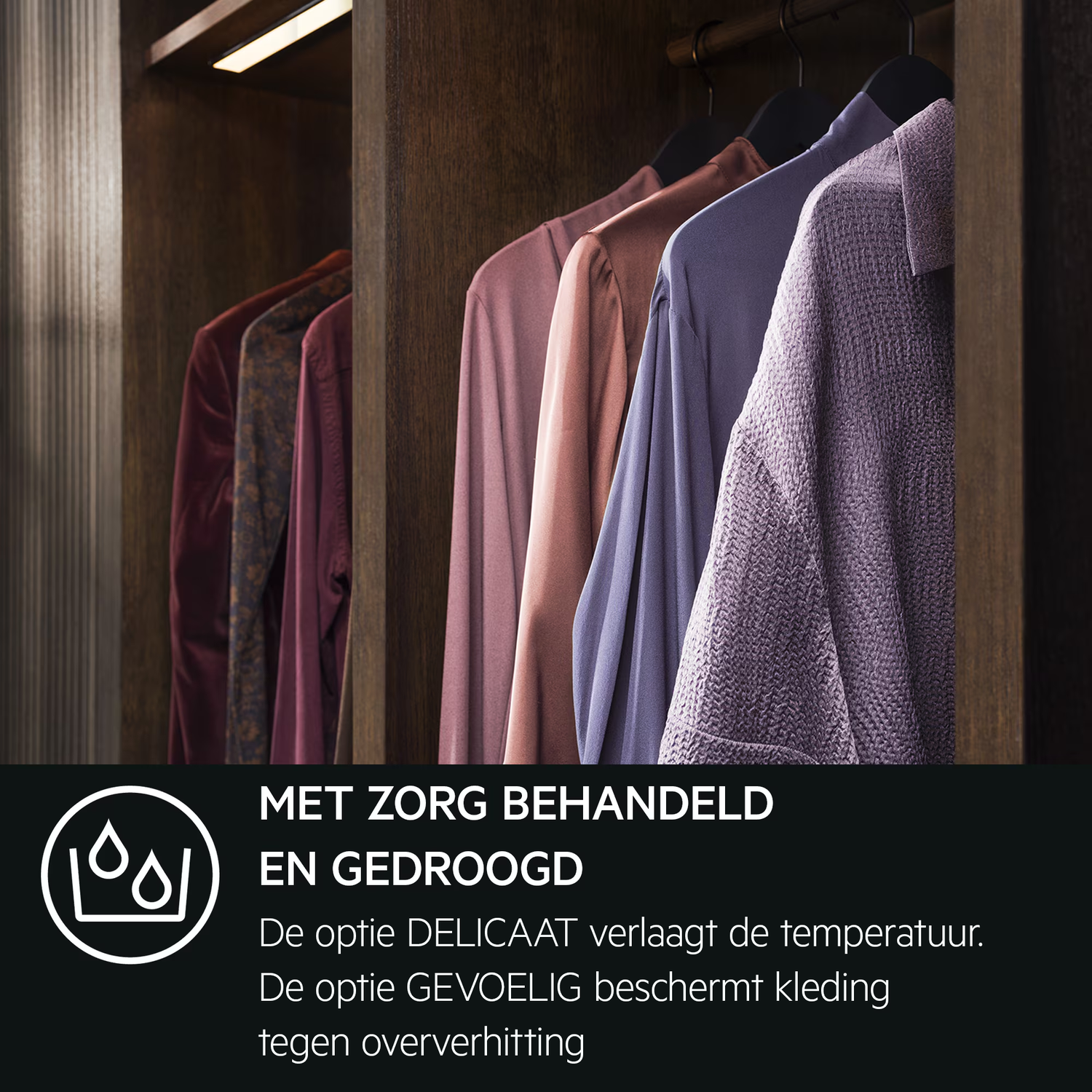 Clothes hanging in a wooden closet. Various colored shirts and jackets are on hangers. The closet is open with a light above.
