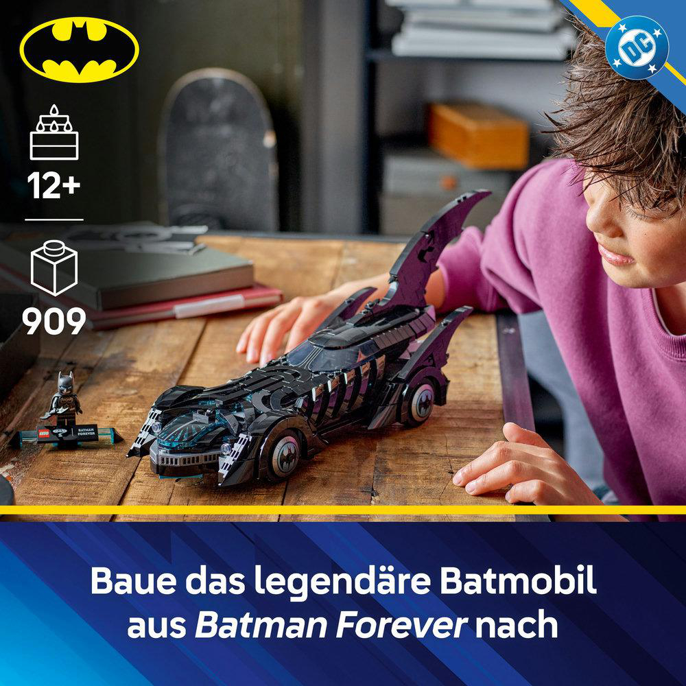 Ein Lego Batmobil aus Batman Forever auf einem Holztisch. Die Hände einer Person sind in der Nähe des Autos. Der Hintergrund hat Logos und Text.