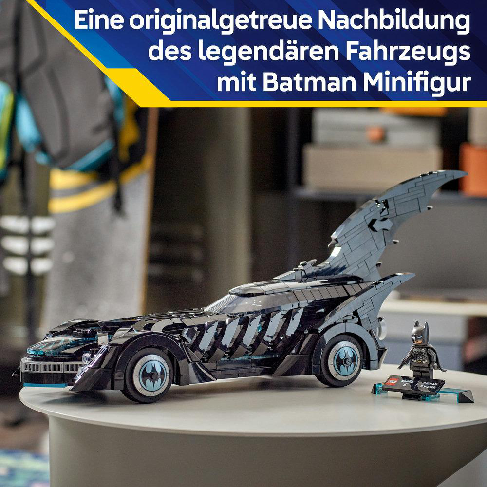 Schwarzes Lego Batmobil mit Batman-Minifigur auf einem weißen Tisch. Das Auto ist detailliert und hat eine große Finne. Der Hintergrund ist verschwommen.