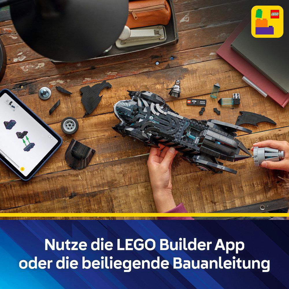 Eine Person, die ein schwarzes Lego Batmobil auf einem Holztisch zusammenbaut, mit Anweisungen auf einem Tablet. Lego-Logo ist sichtbar.