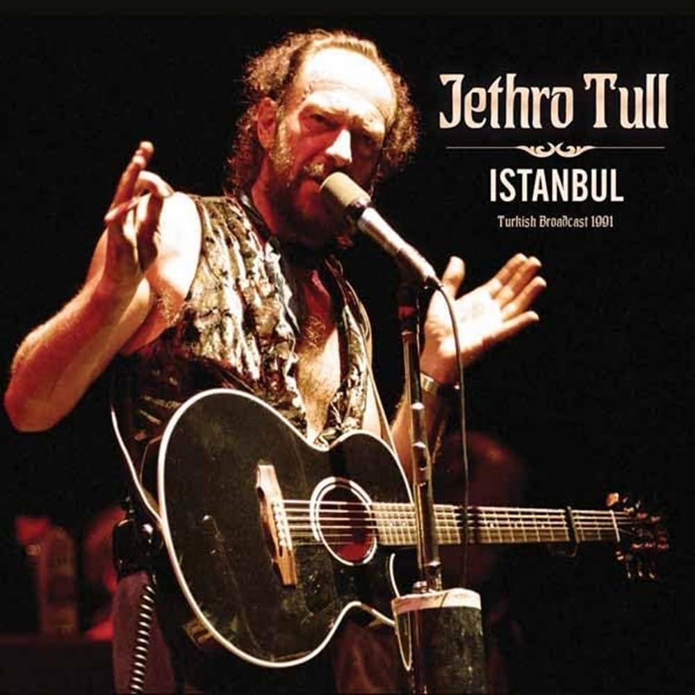 Férfi gitározik a színpadon. Jethro Tull Isztambul. Fekete gitár, mikrofon. Sötét háttér, színpadi fények. Koncert.