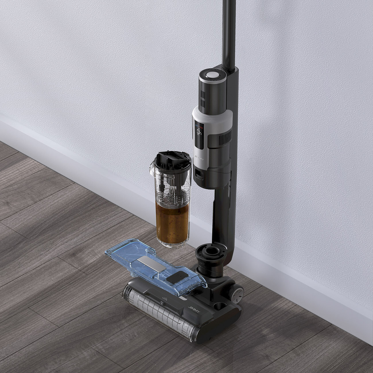 Czarno-szary odkurzacz opiera się o białą ścianę na drewnianej podłodze. Części są odłączone, pokazując zbiornik na wodę.