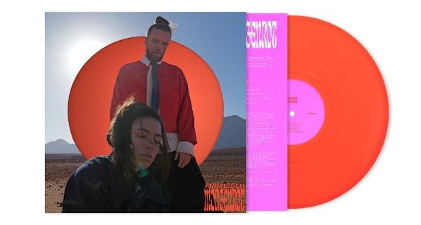 Albumcover mit zwei Personen vor einem Wüstenhintergrund. Auf der rechten Seite befindet sich eine orangefarbene Schallplatte.
