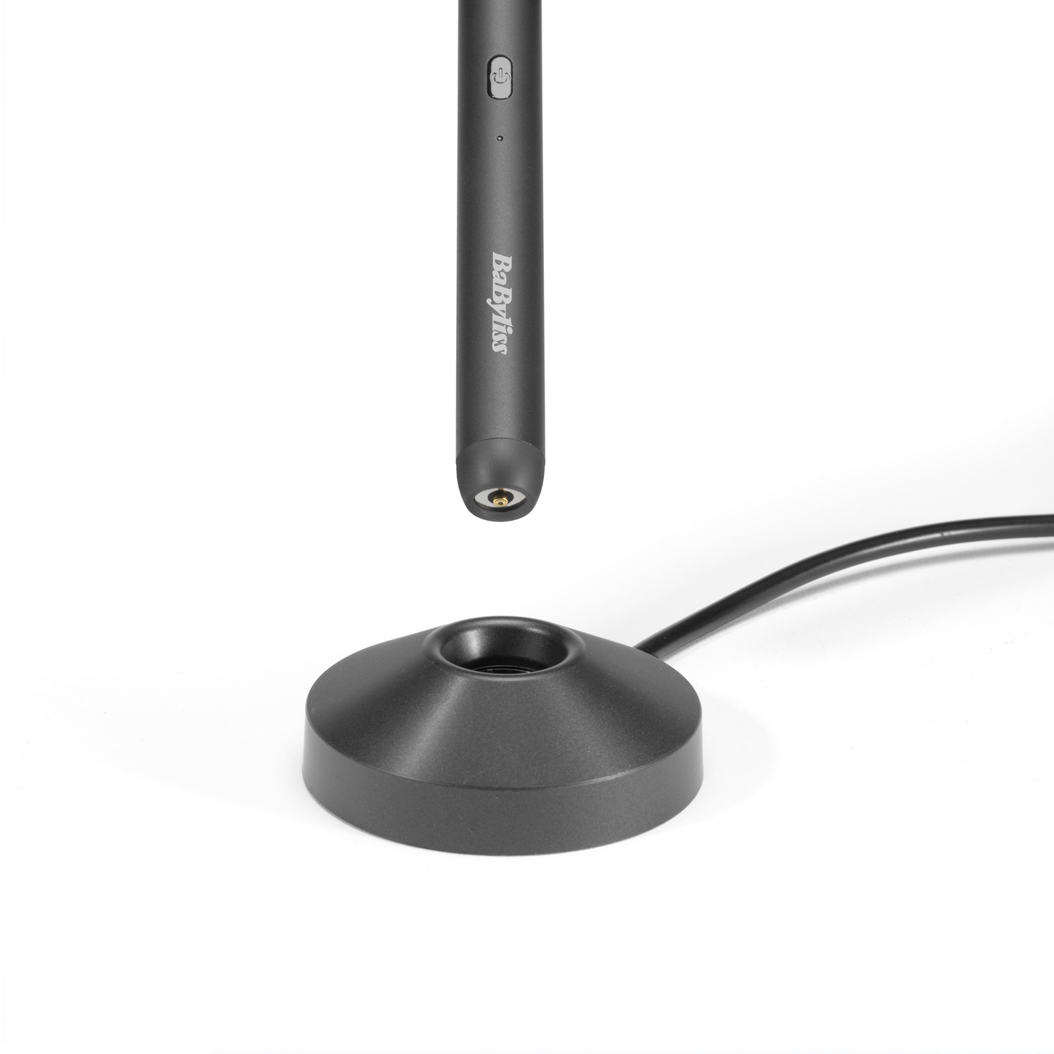 Una herramienta de peinado negra está encima de su base negra. La herramienta tiene la marca BaByliss. La base tiene un cable negro.