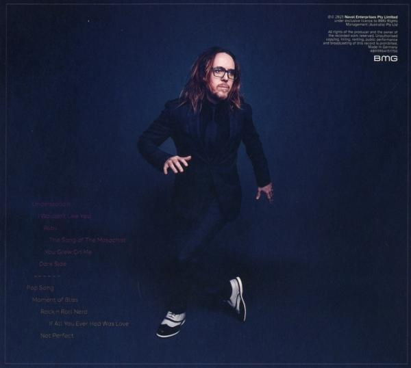 Mann in schwarzem Anzug springt vor blauem Hintergrund. Er trägt eine Brille und Turnschuhe. Album-Trackliste links.