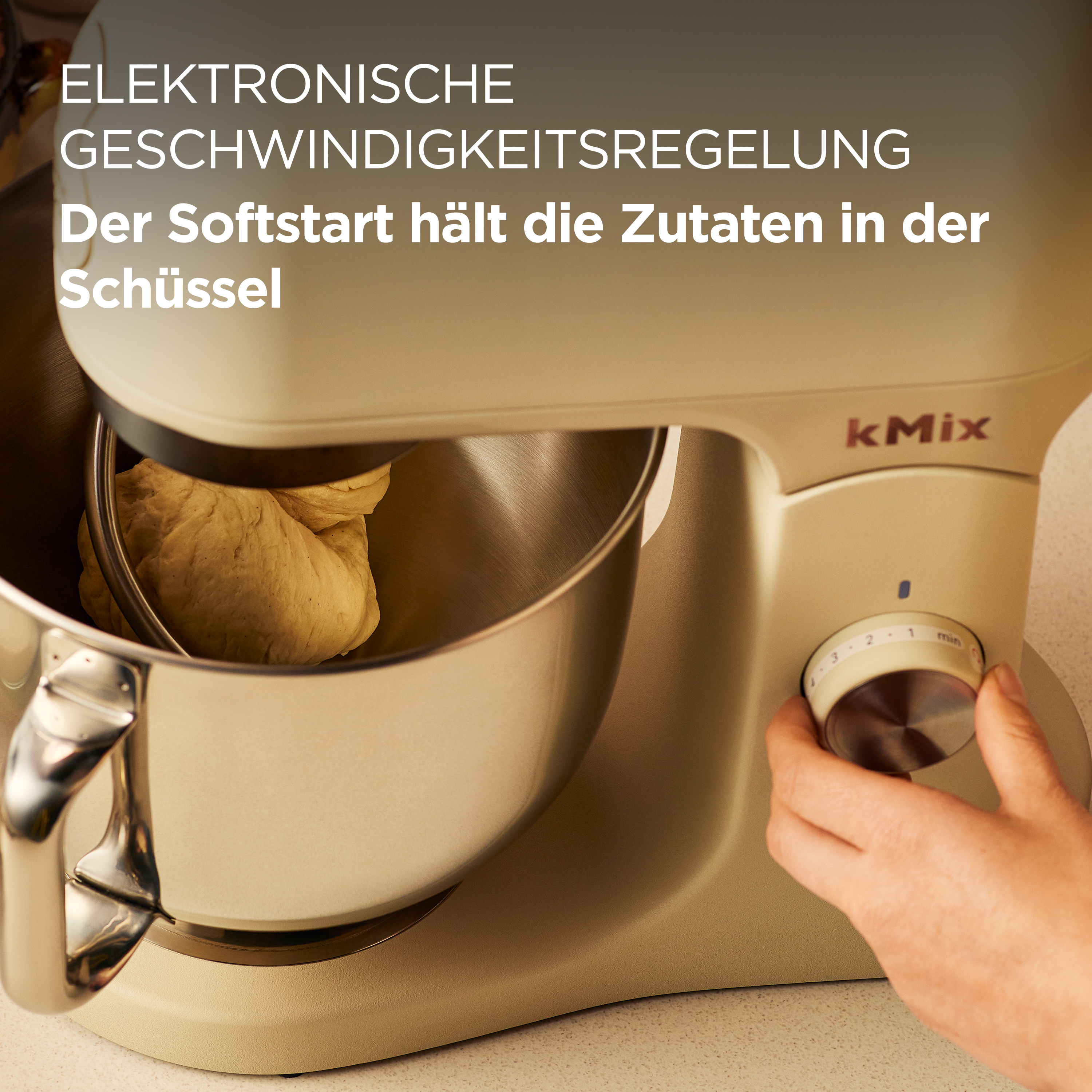 Ein beiger kMix-Küchenmixer mit Teig im Inneren. Eine Hand dreht den Drehzahlregler.