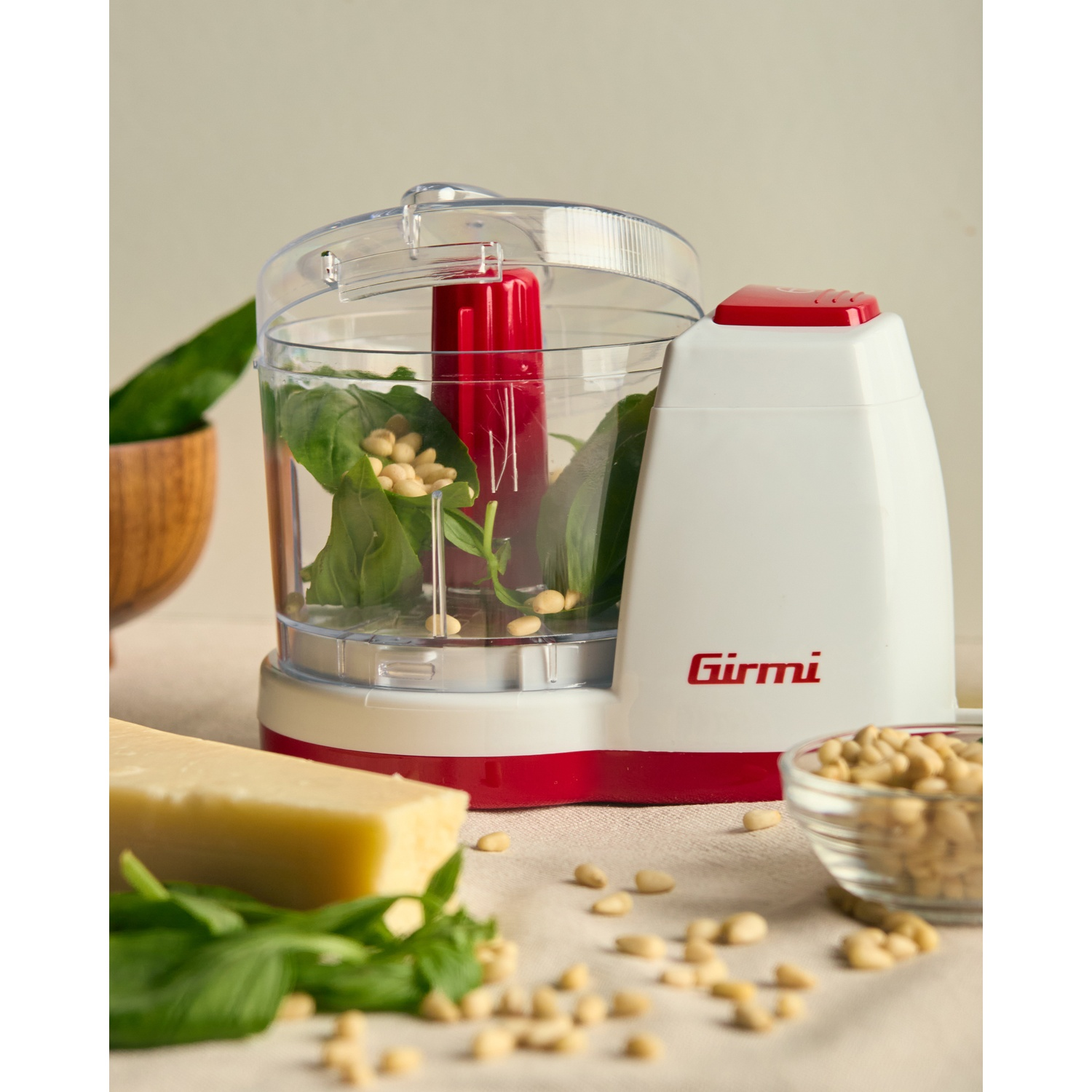 Robot da cucina con basilico, pinoli e formaggio. Robot bianco e rosso su un tavolo con ingredienti.