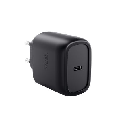 Egy fekete Trust USB-C töltő. Egy oldalon dugó, elöl USB-C port található. A háttér fekete.