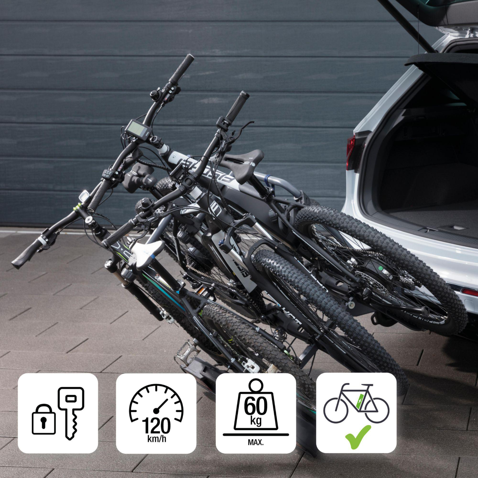 Drei schwarze Fahrräder sind am Kofferraum eines Autos befestigt. Symbole zeigen Schlüsselschloss, 120 km/h, 60 kg max und E-Bike-Kompatibilität.