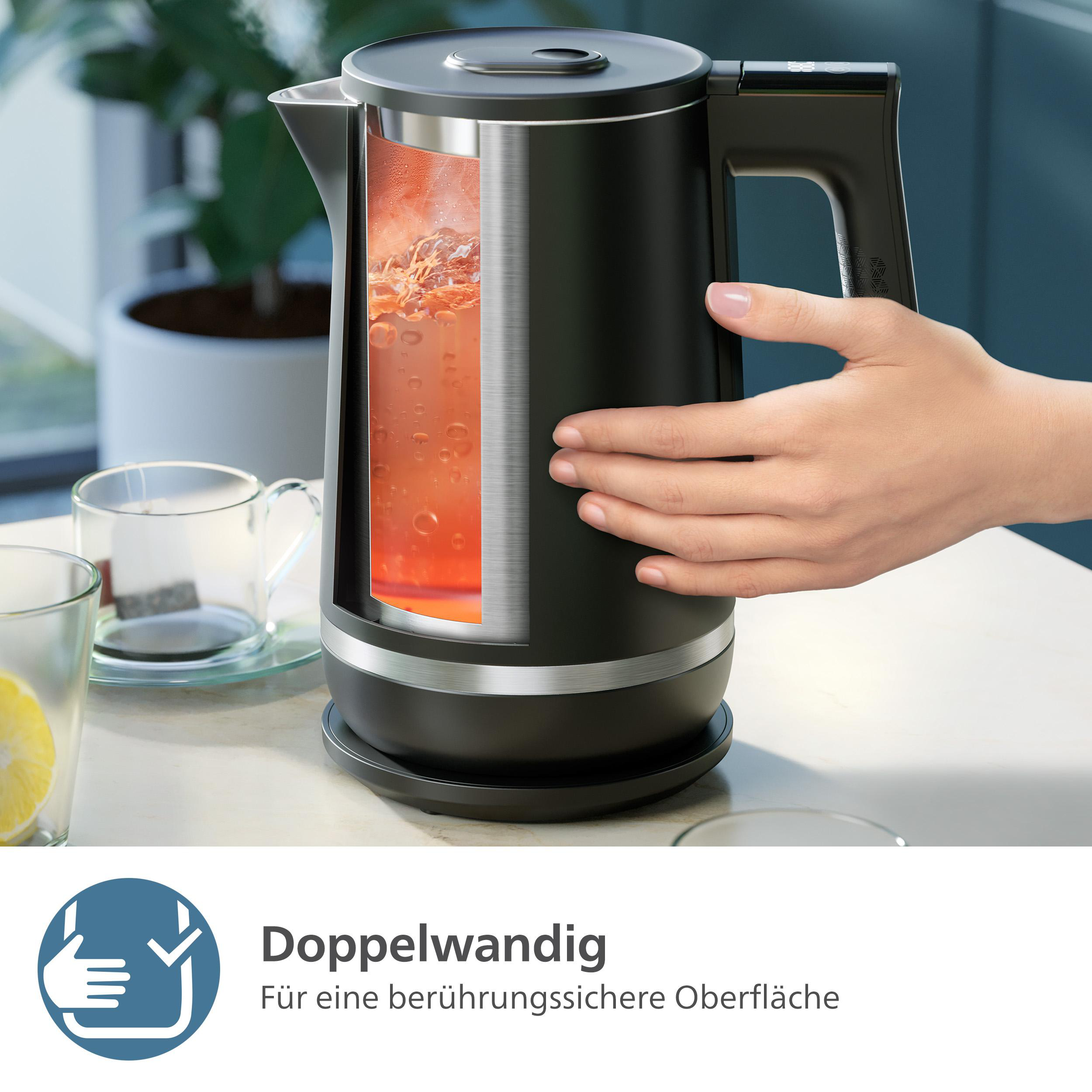 Ein schwarzer Wasserkocher mit einem Ausschnitt, der kochendes Wasser zeigt. Eine Hand berührt den Wasserkocher. Gläser und eine Zitronenscheibe sind sichtbar.