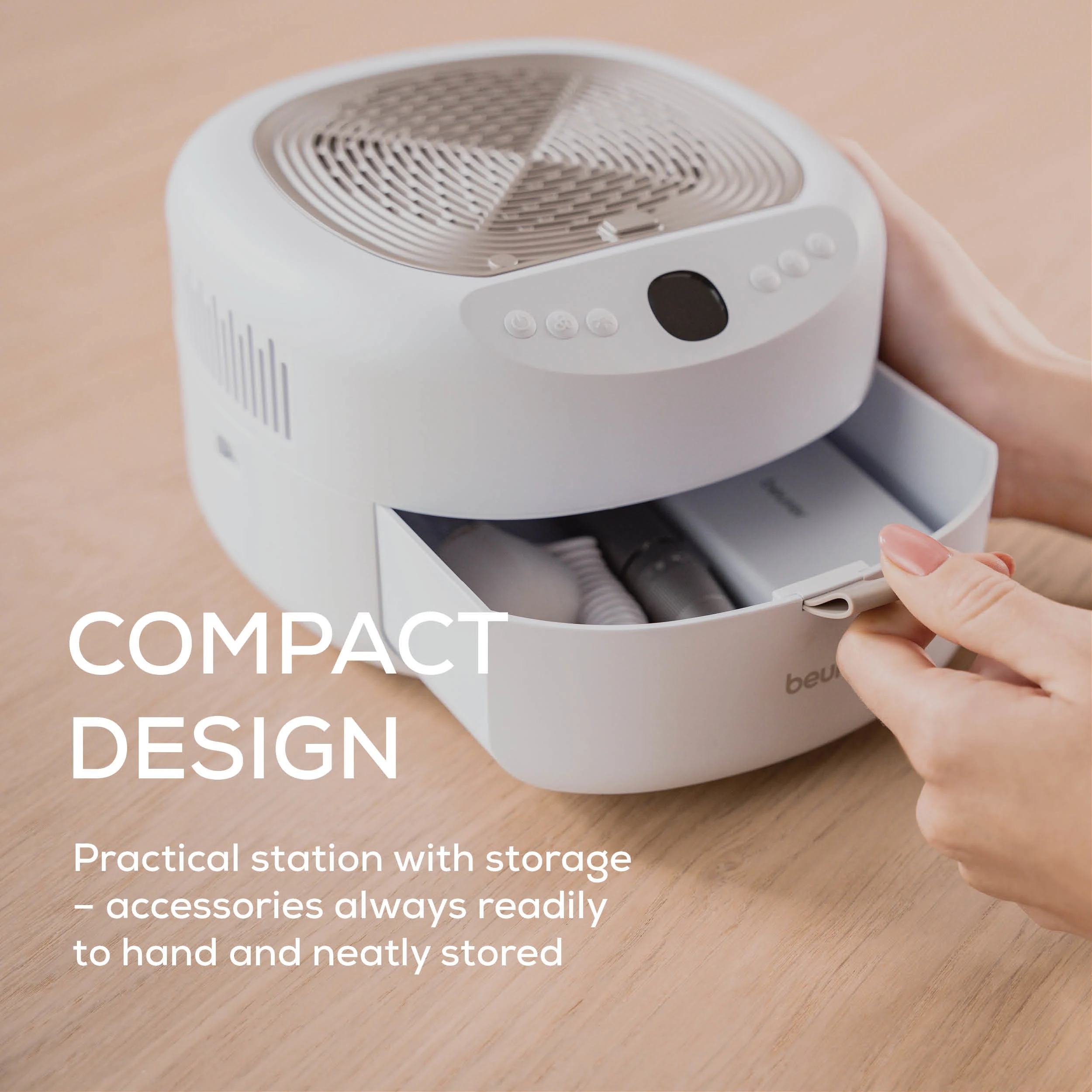 Ein weißes Gerät mit einer Schublade ist geöffnet und zeigt Zubehör. Eine Hand öffnet die Schublade. Text lautet 'Compact Design'.