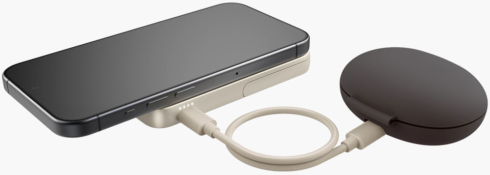 Un smartphone repose sur un socle de chargement beige, relié à un appareil circulaire marron foncé par un câble beige.