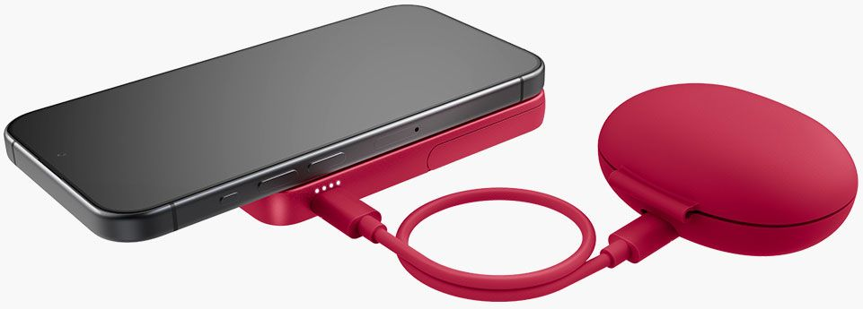 Un smartphone noir repose sur un socle de chargement rouge. Un câble de chargement rouge se connecte à une batterie externe circulaire rouge.