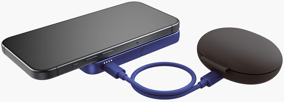 Un smartphone noir est sur un socle de chargement bleu. Un étui gris foncé et un câble bleu sont à droite. Le téléphone charge.