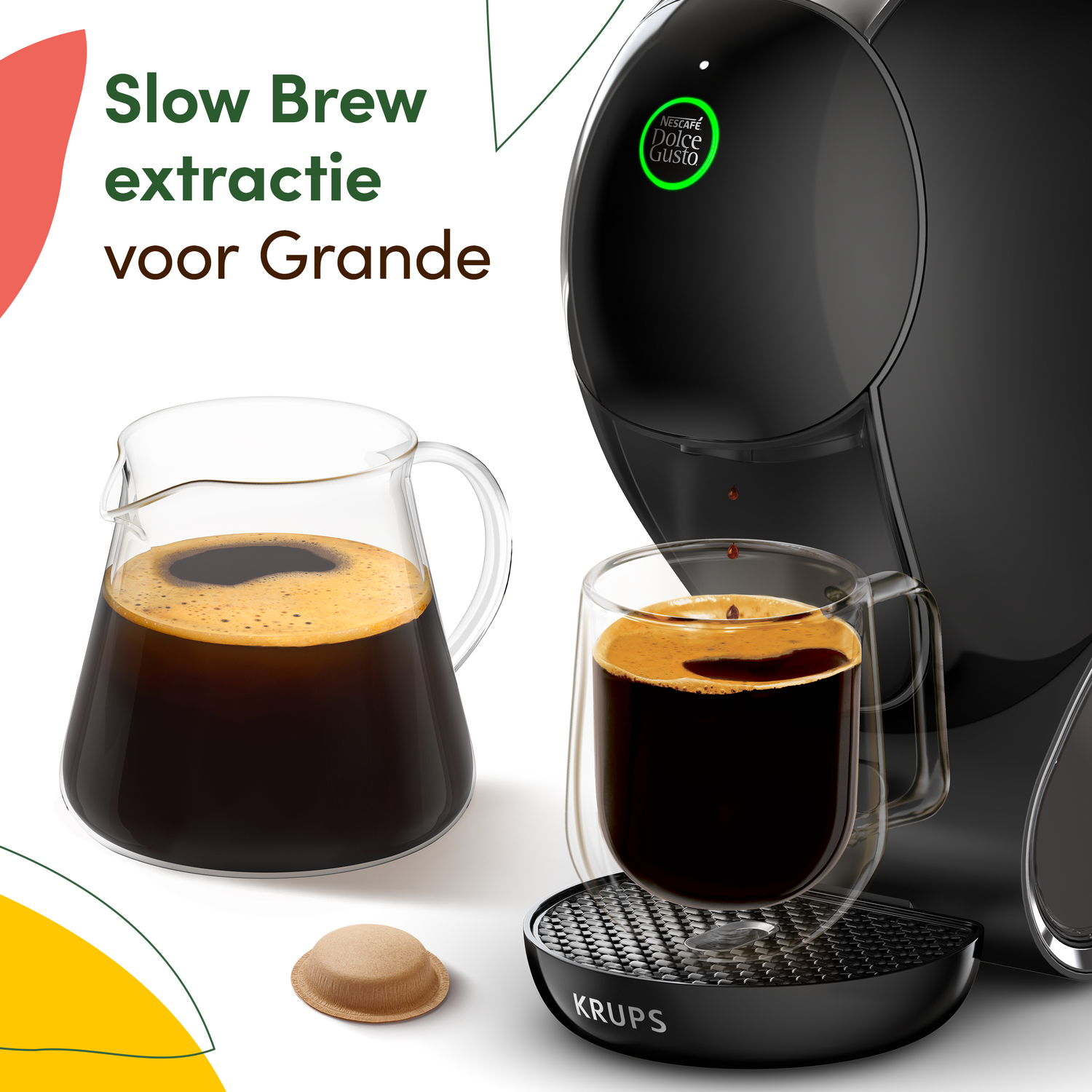 A black Dolce Gusto coffee machine with a glass of coffee and a coffee pod. A glass pitcher with coffee sits beside it.