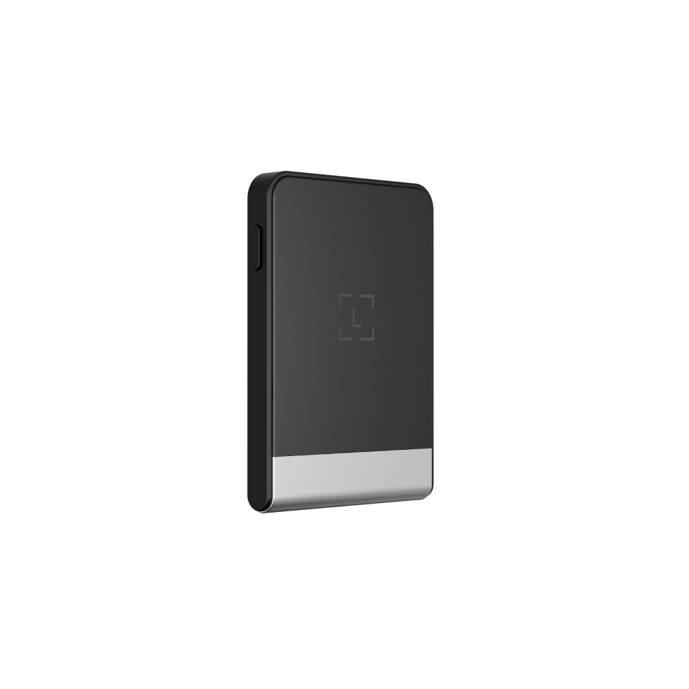 Un dispositivo pequeño y rectangular con la parte superior negra y la inferior plateada, centrado sobre un fondo negro. Tiene un logotipo cuadrado.