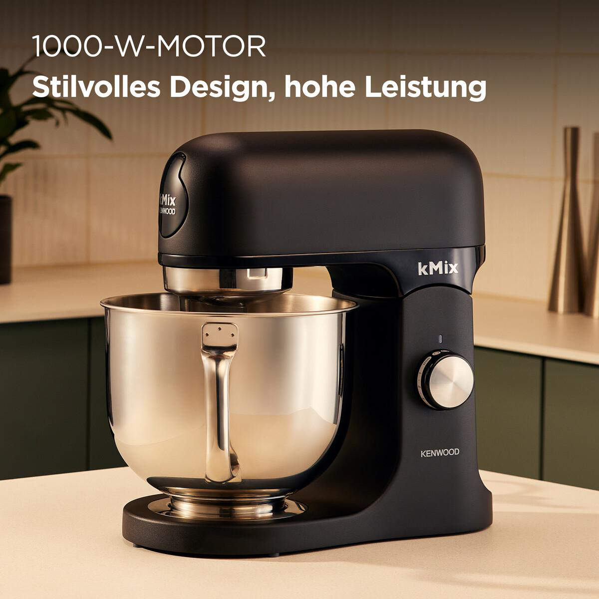 Ein schwarzer Kenwood kMix-Küchenmixer mit einer Edelstahlschüssel steht auf einer Theke. Der Text lautet: '1000-W-MOTOR, Stilvolles Design, hohe Leistung'.