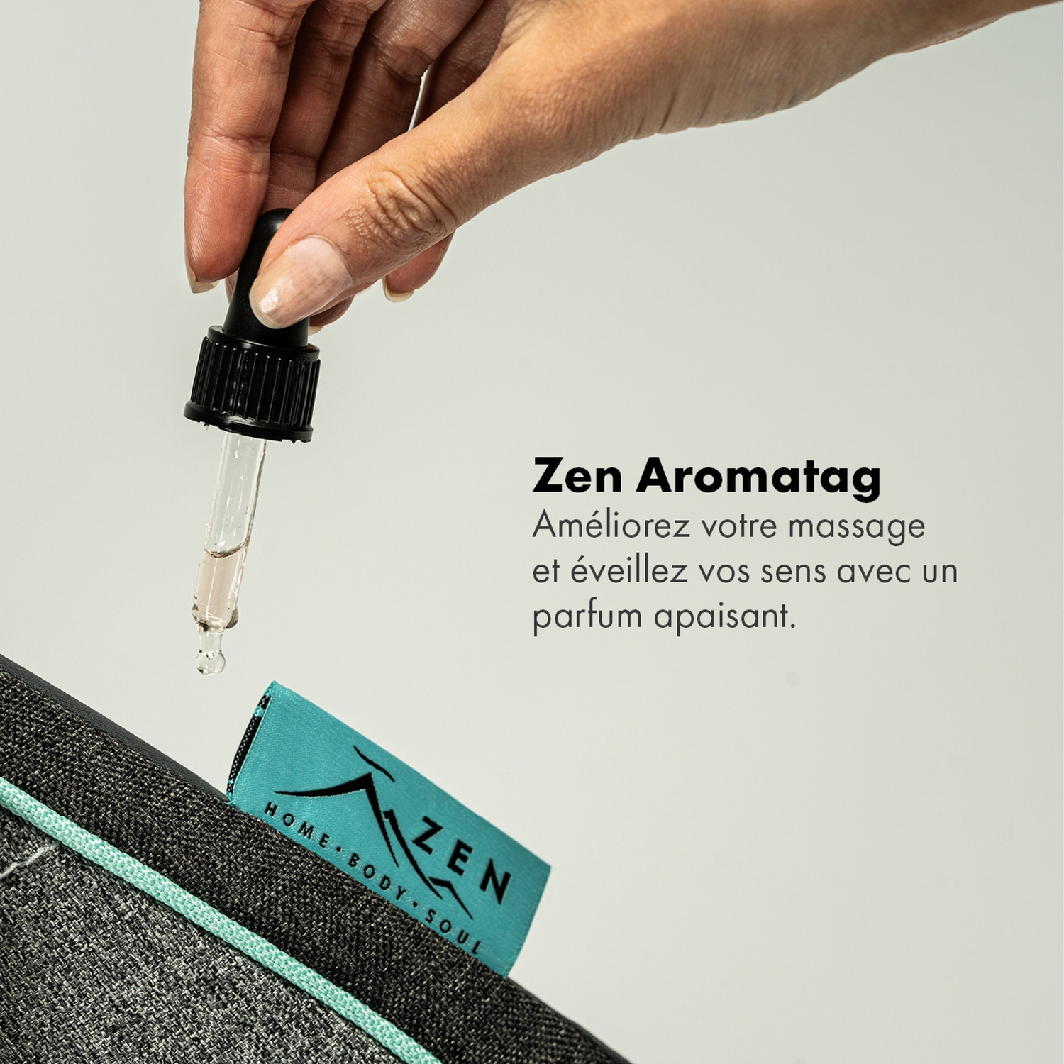 Une main avec une pipette libère du liquide sur un tapis. Le tapis est gris avec une couture turquoise et une étiquette indiquant 'ZEN'.