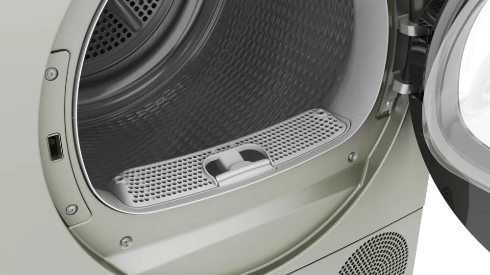 Otwarty bęben suszarki z filtrem i uchylonymi drzwiami. Wnętrze jest ciemne, a na zewnątrz jasny metaliczny kolor.