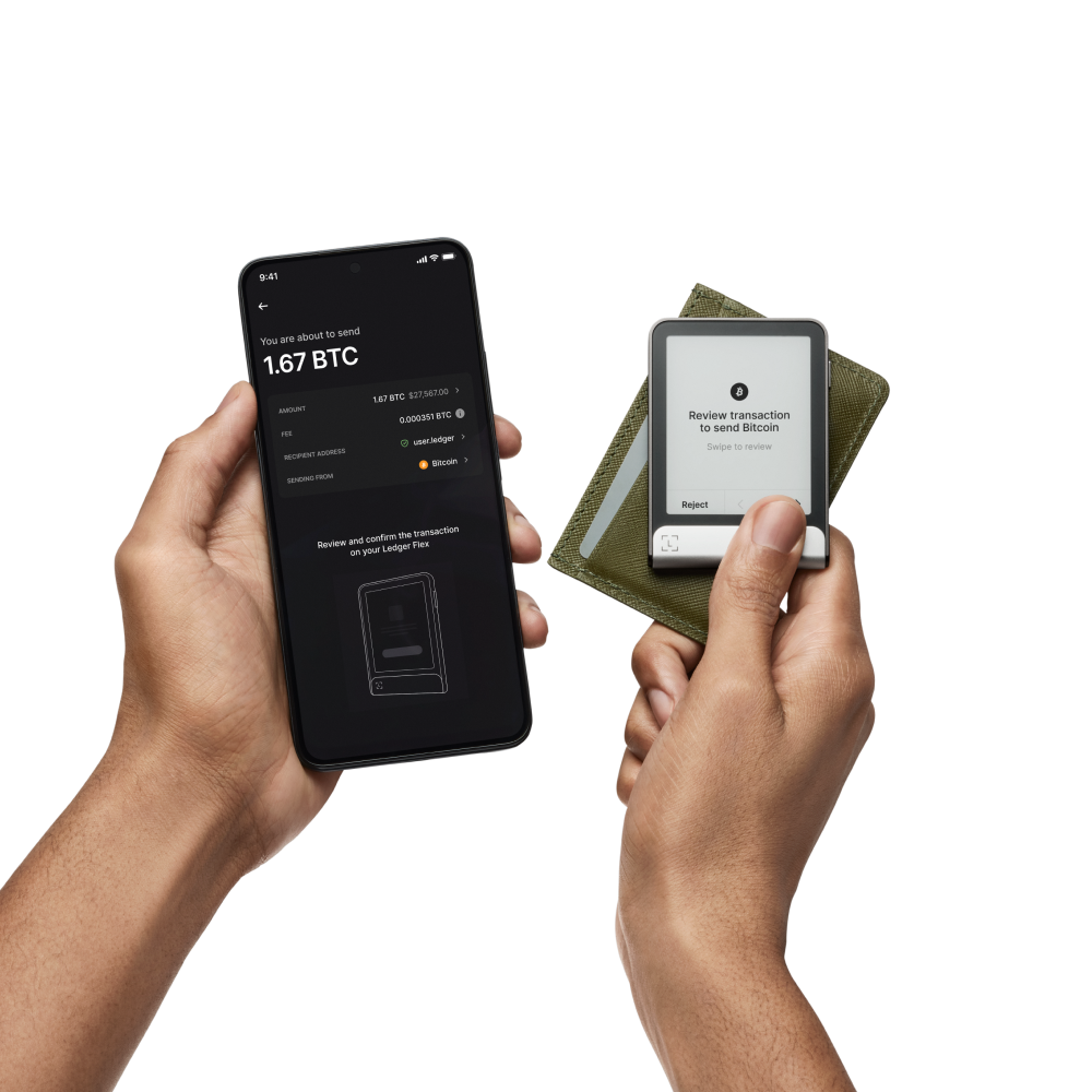 Manos sosteniendo un teléfono y un dispositivo Ledger. El teléfono muestra una transacción BTC y el Ledger la confirma. Detrás del Ledger hay una cartera.