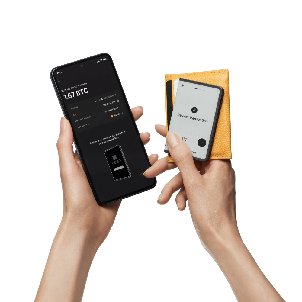 Manos sosteniendo un teléfono y un pequeño dispositivo. El teléfono muestra una transacción de bitcoin, el dispositivo muestra la revisión.