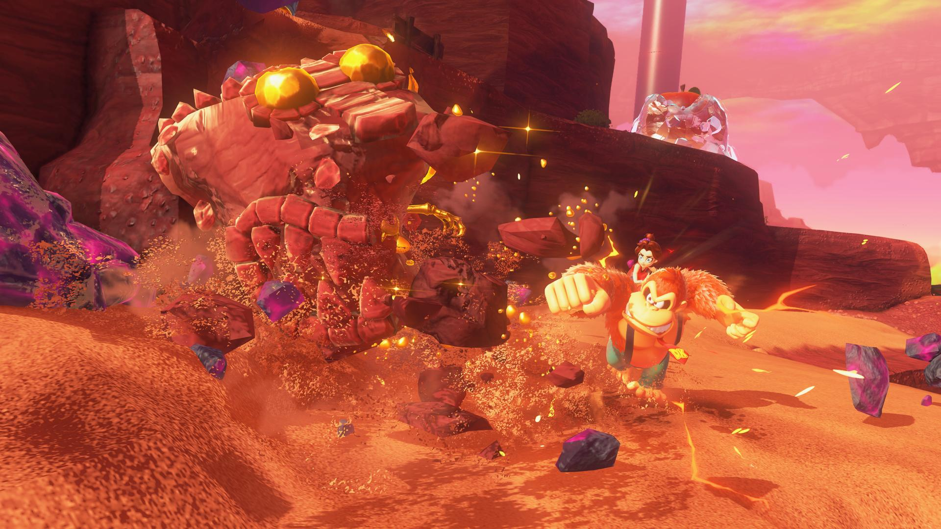 Donkey Kong schlägt ein Felsmonster. Ein Mädchen reitet auf seinem Rücken. Felsen und Kristalle fliegen. Der Hintergrund zeigt einen rosa Himmel und Klippen.