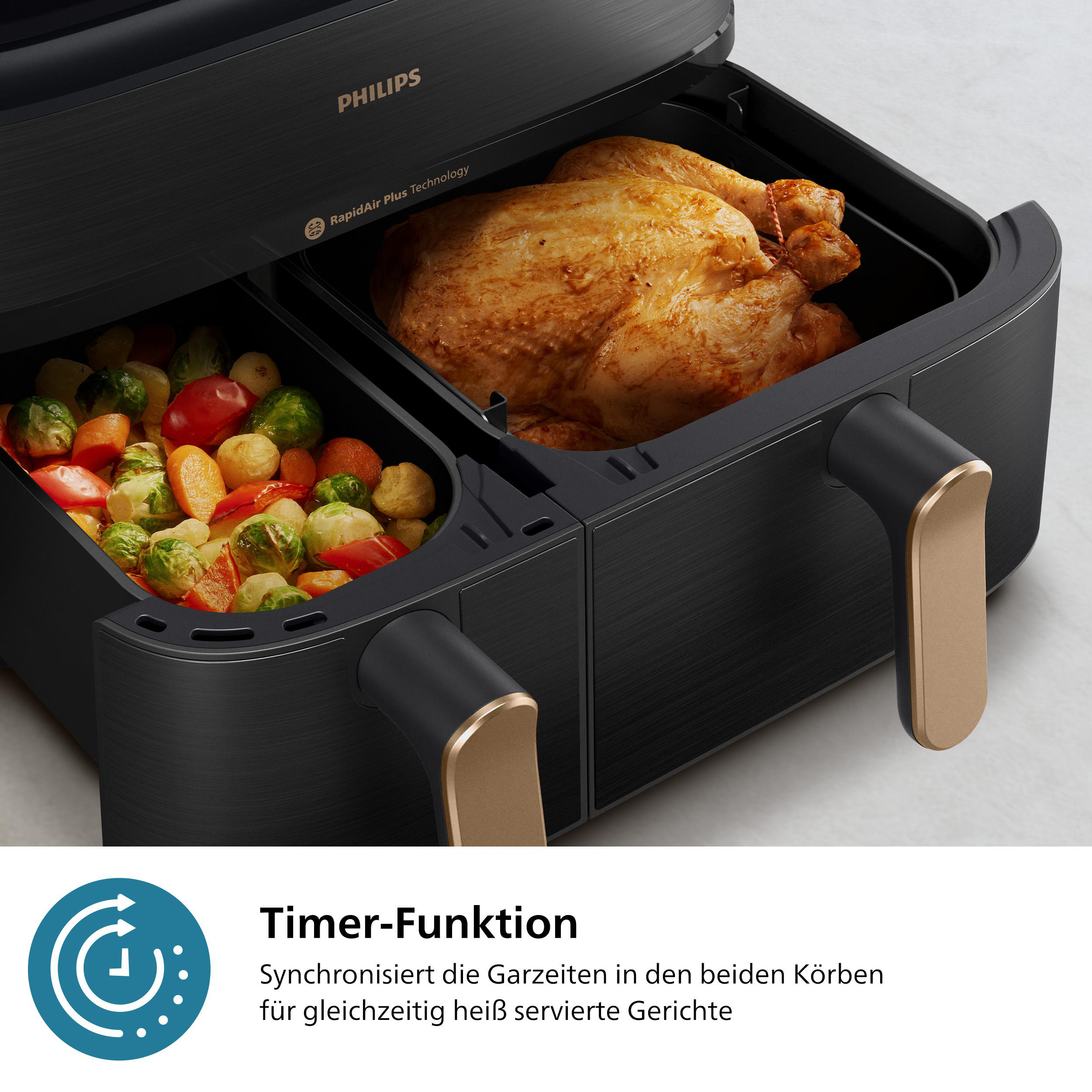 Ein schwarzer Philips-Heißluftfritteuse mit zwei Fächern. Eines hat ein gebratenes Hähnchen, das andere Gemüse.