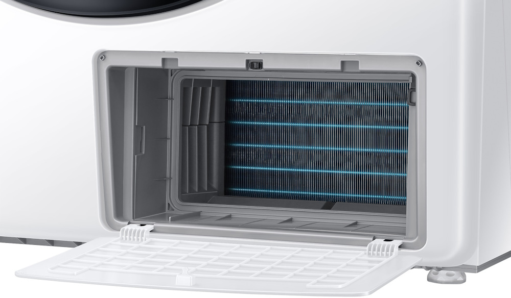 A washing machine's open filter compartment. Inside, a dark filter with parallel lines is visible. The door is open.