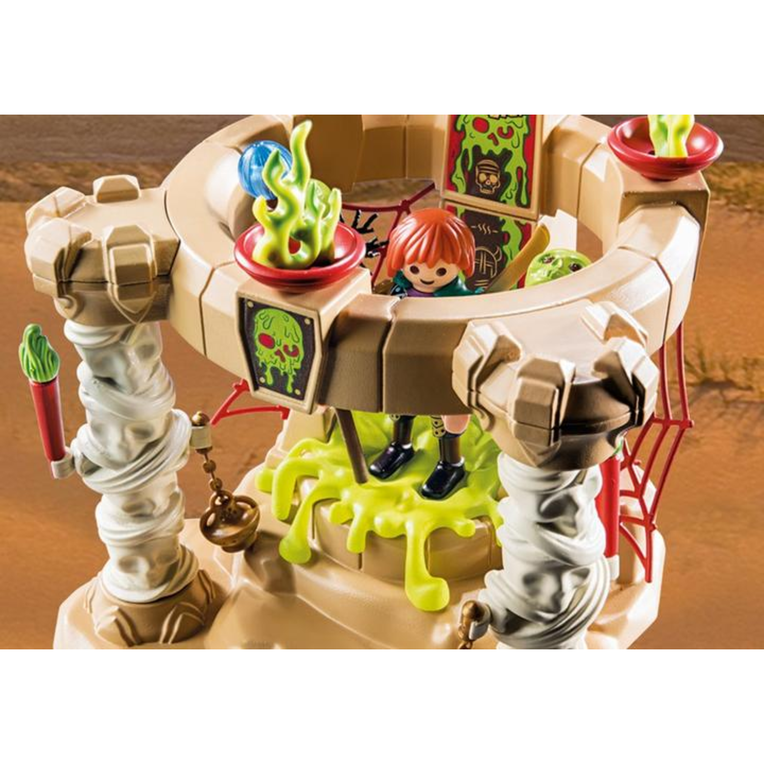 Een speelgoedkasteel met een kinderfiguur, groene vlammen en slijm. Het kasteel heeft een bruine buitenkant, een rood spinnenweb en witte pilaren.