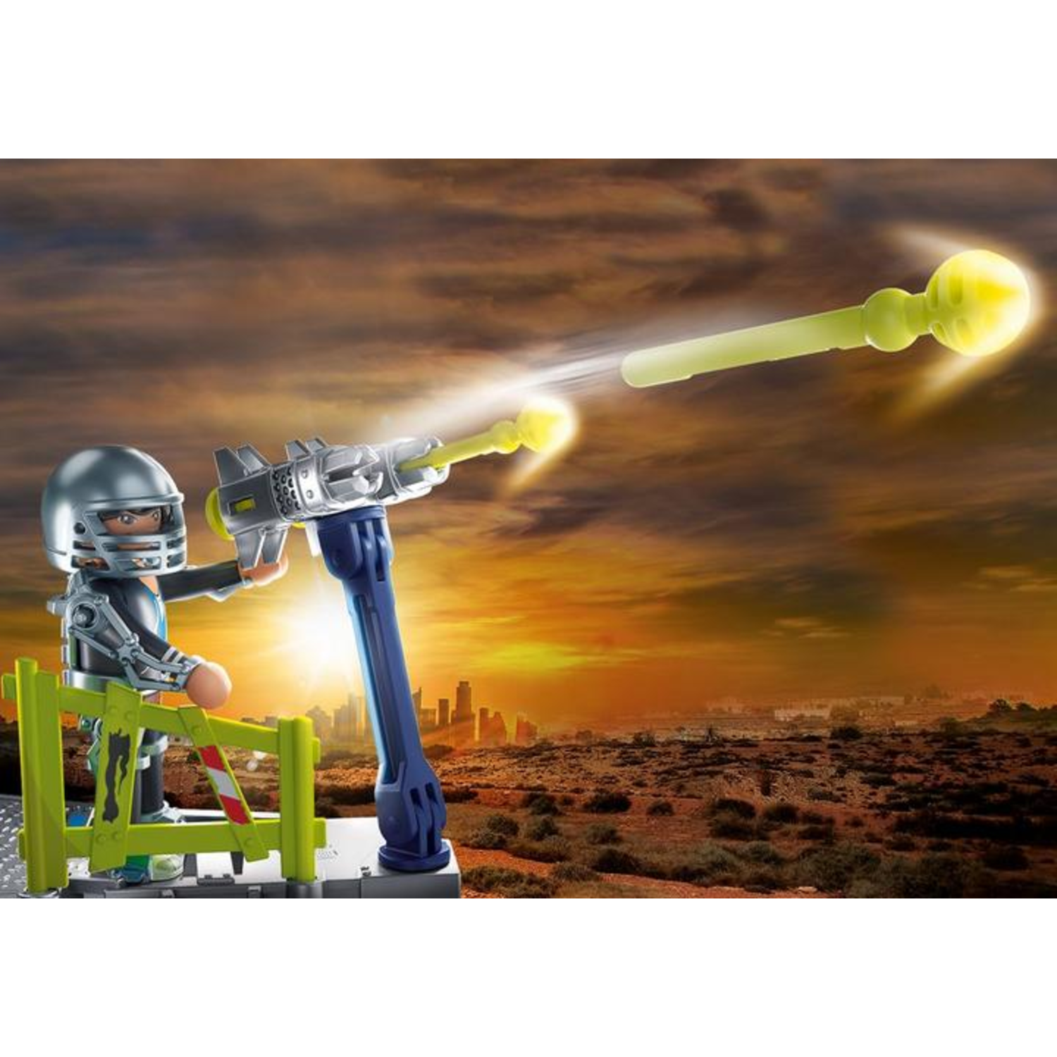 A toy figure in a helmet operates a ray gun. The background features a sunset over a city and dry land with sparse vegetation.