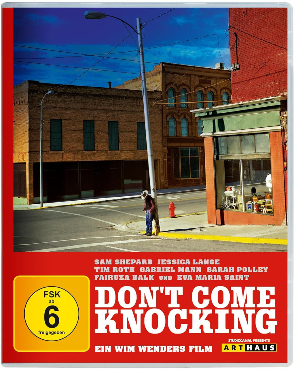DVD-Cover für 'Don't Come Knocking' mit Straßenszene. Ein Mann steht an einem Pfosten. Gebäude und ein roter Hydrant sind sichtbar.