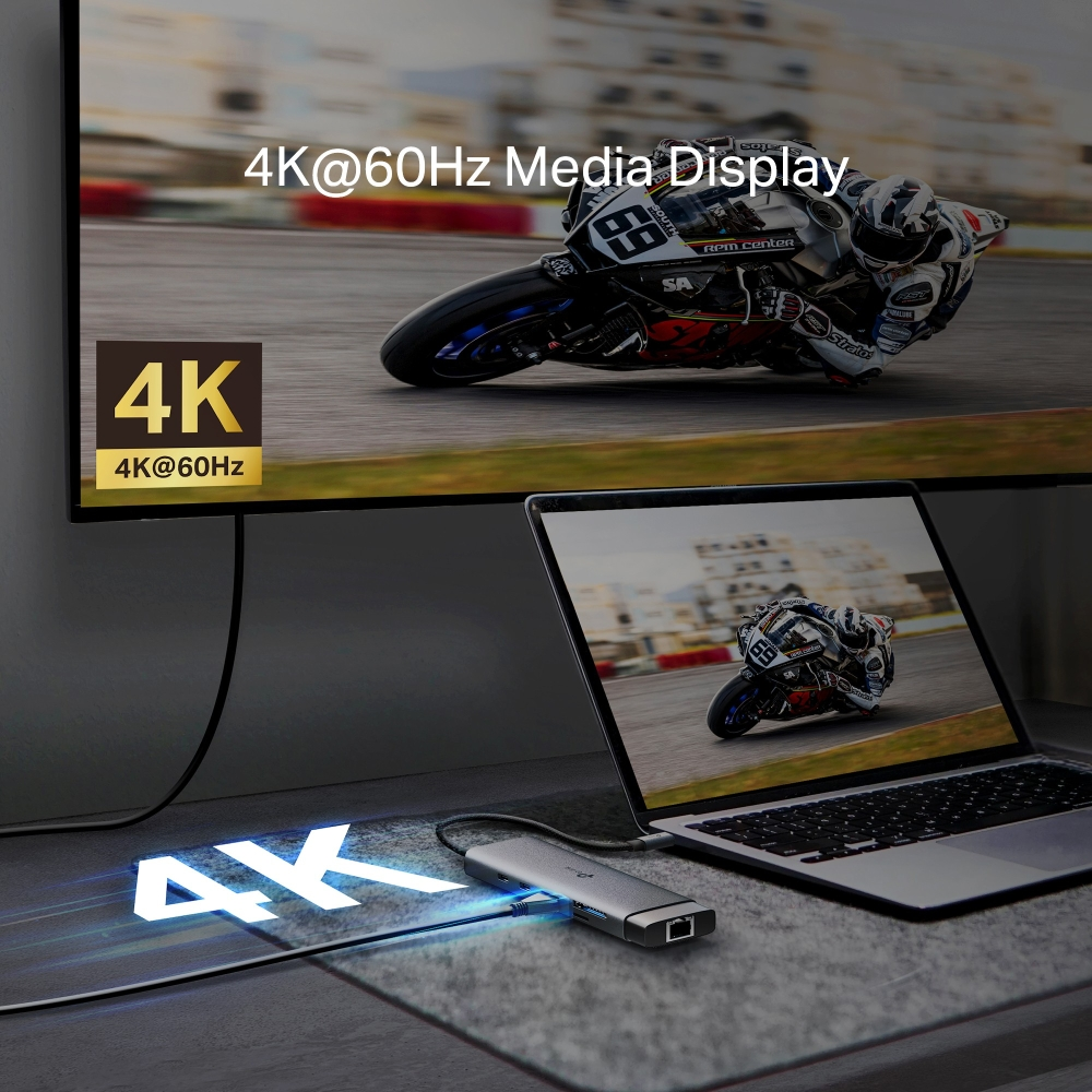 Bir dizüstü bilgisayar, ekran ve hub bağlı. Ekranlar bir motosiklet yarışı gösteriyor. 4K ve 4K@60Hz metinleri görünür.