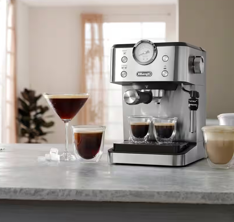 Srebrny ekspres do kawy z dwoma szklankami kawy, kieliszkiem do koktajli i szklanką latte na marmurowym stole.