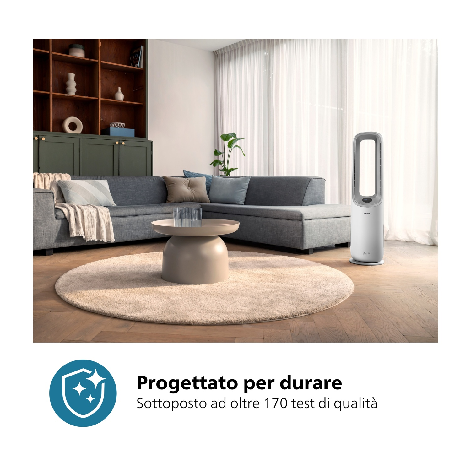 Un moderno soggiorno con divano grigio, tappeto rotondo e ventilatore bianco. Tavolino con vetro. Dietro, un mobile.