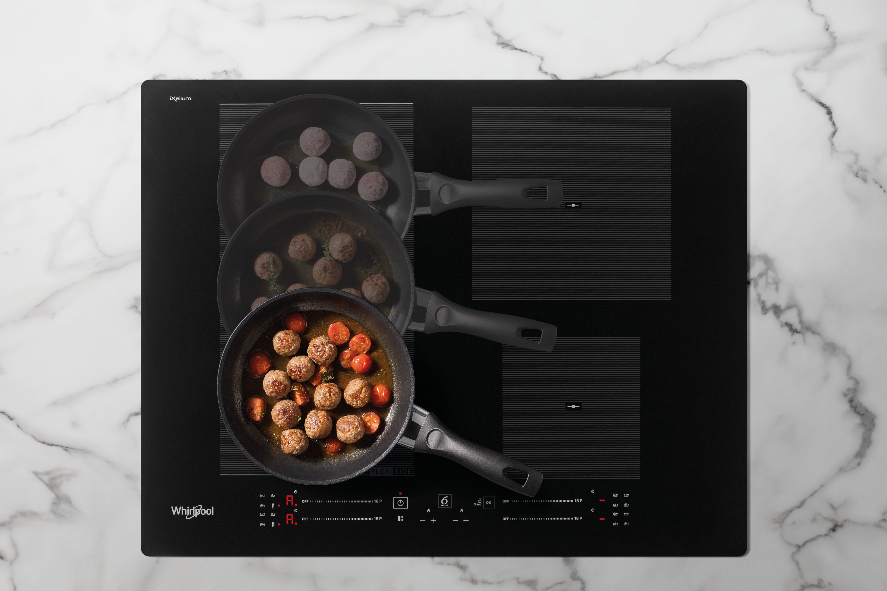 Czarna płyta indukcyjna z trzema patelniami. Jedna patelnia ma klopsiki z pomidorami, a dwie z klopsikami.