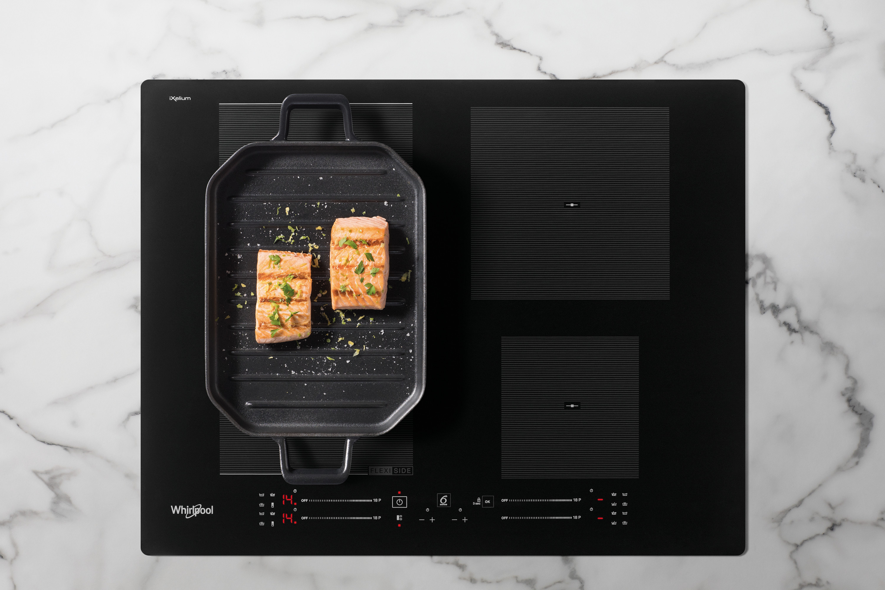 Czarna płyta indukcyjna z grillowanym łososiem na patelni grillowej. Tło marmurowe.