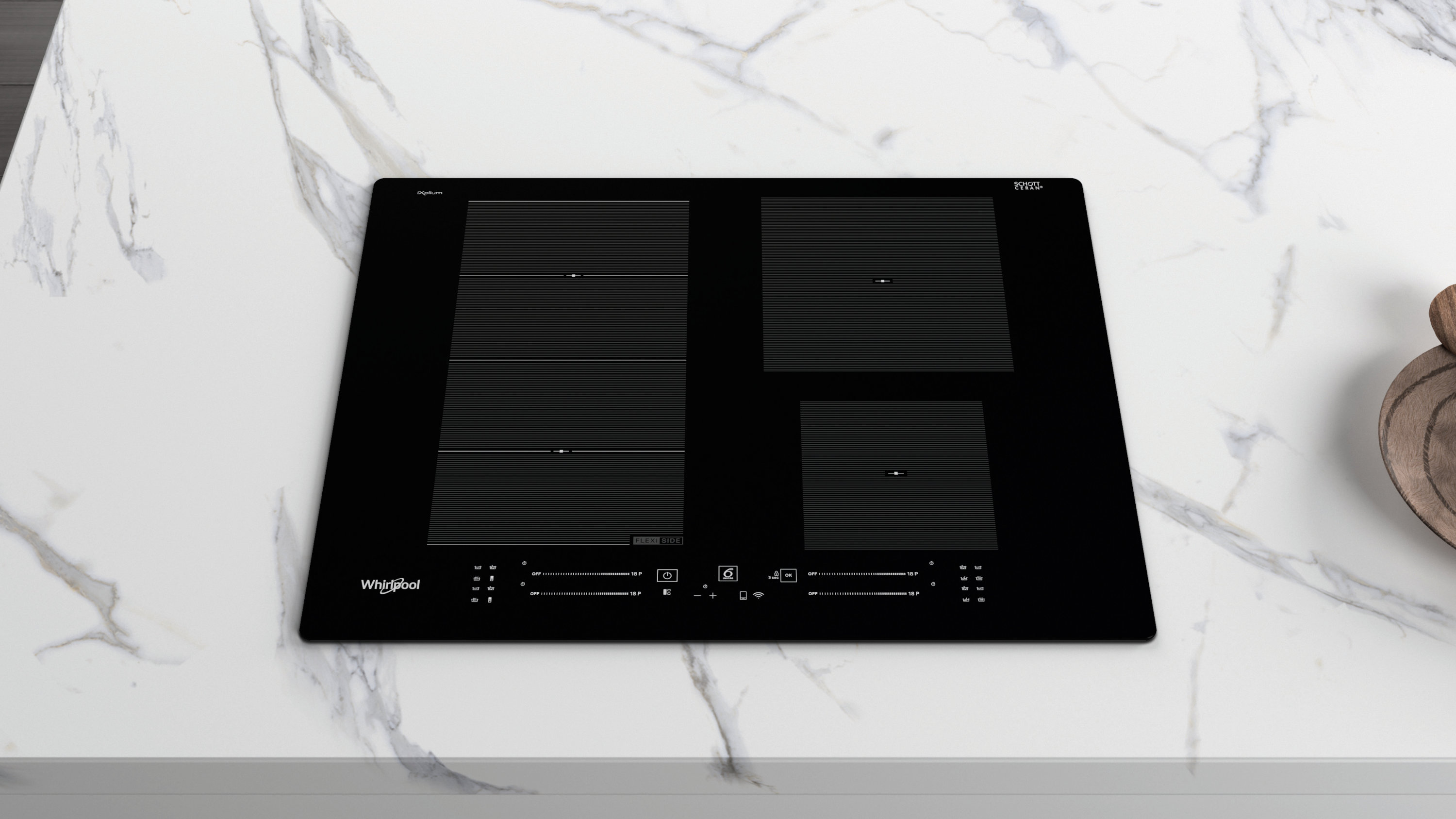 Czarna płyta indukcyjna Whirlpool na białym marmurowym blacie. Cztery strefy gotowania. Drewniana miska po prawej.