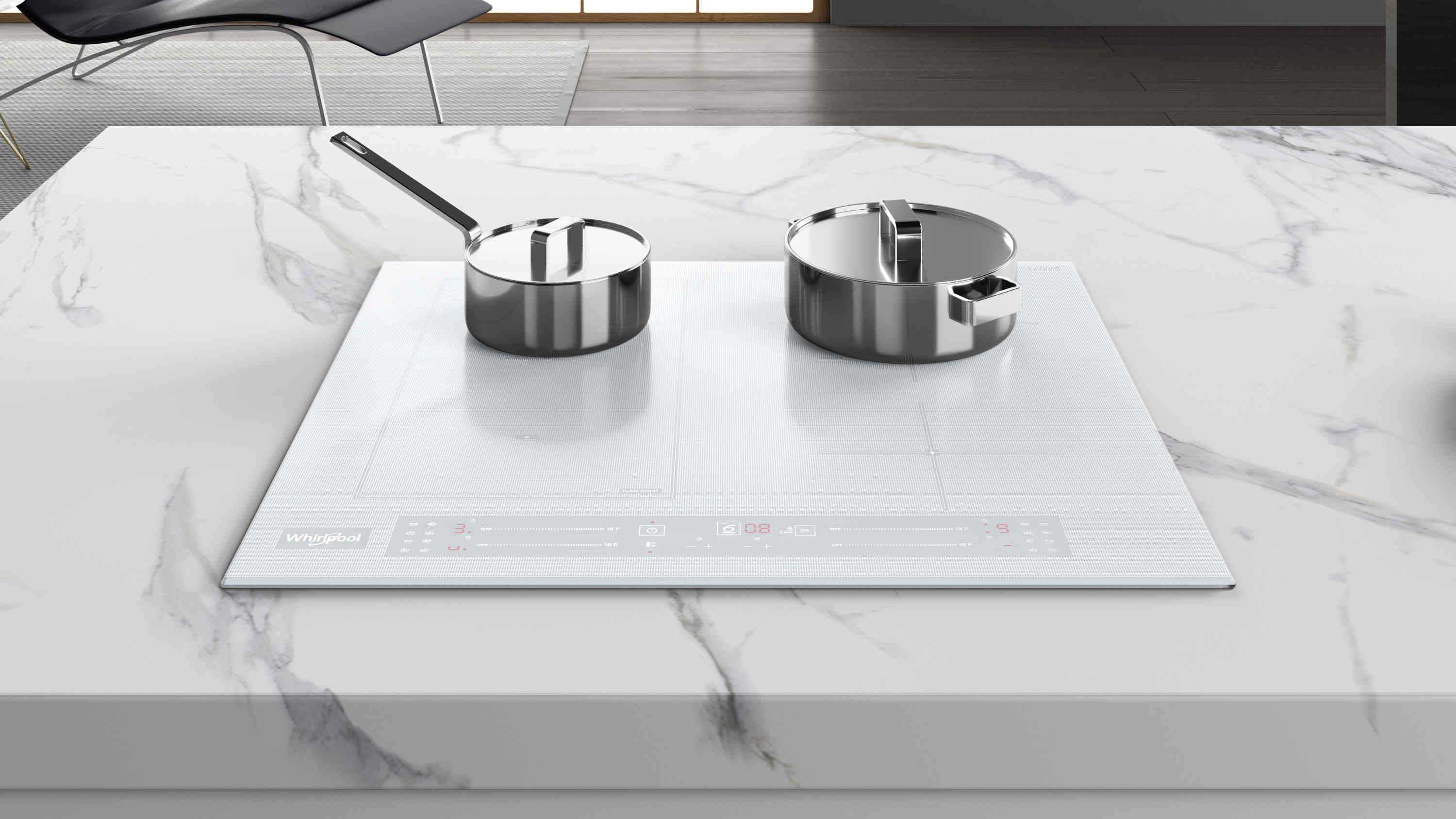 Biała płyta indukcyjna z dwoma garnkami ze stali nierdzewnej na marmurowym blacie. Z tyłu krzesło.