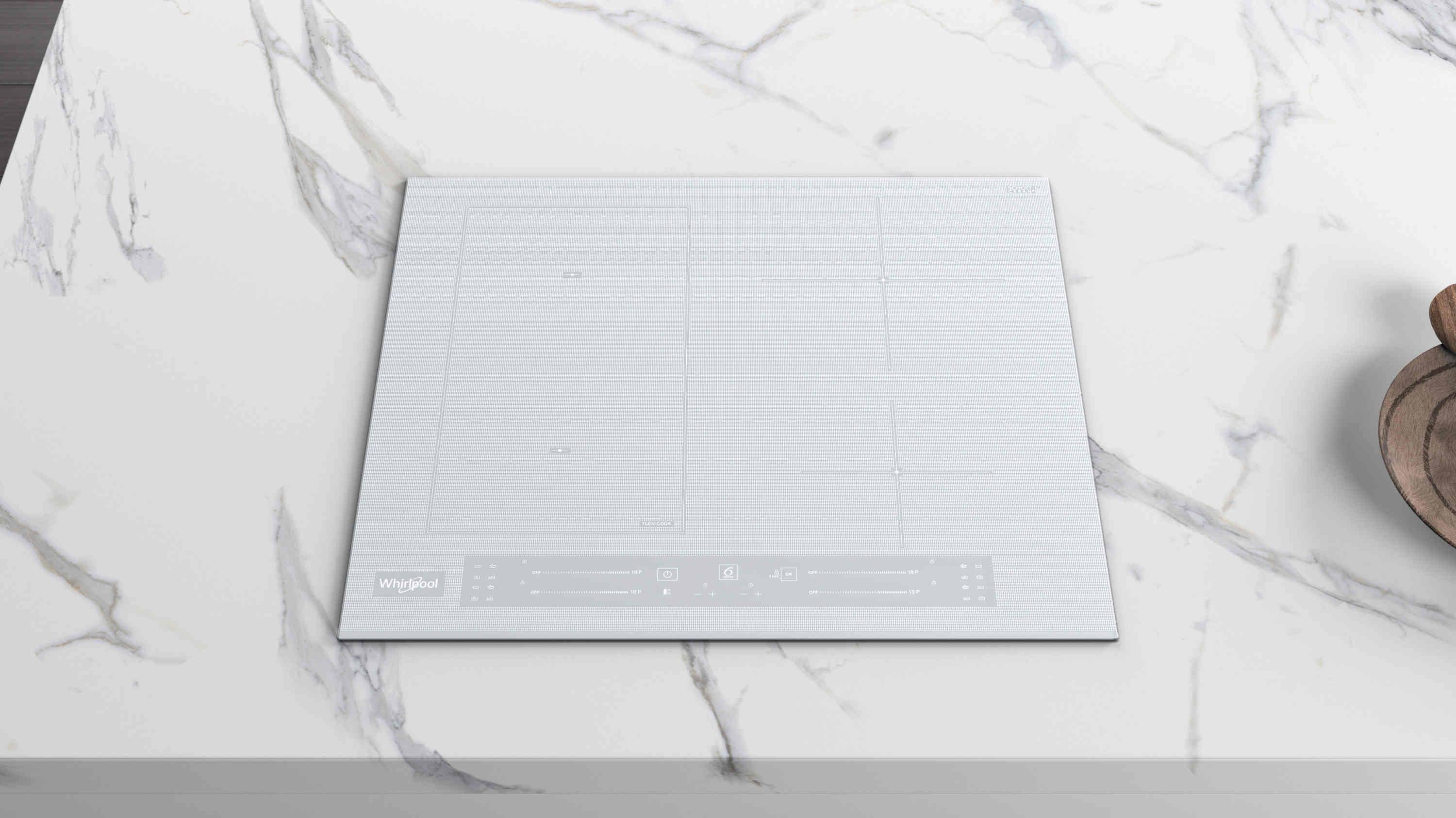 Biała płyta indukcyjna Whirlpool na białym marmurowym blacie. Drewniana miska w tle. Widok z góry.