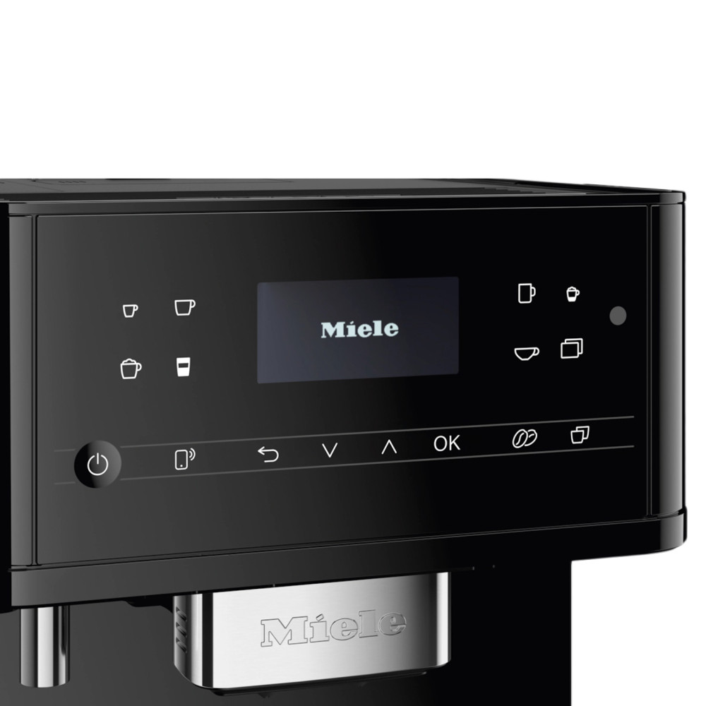 Czarny ekspres do kawy Miele. Ekran wyświetla logo Miele. Widoczne są przyciski opcji kawy. Srebrne logo Miele na dole.