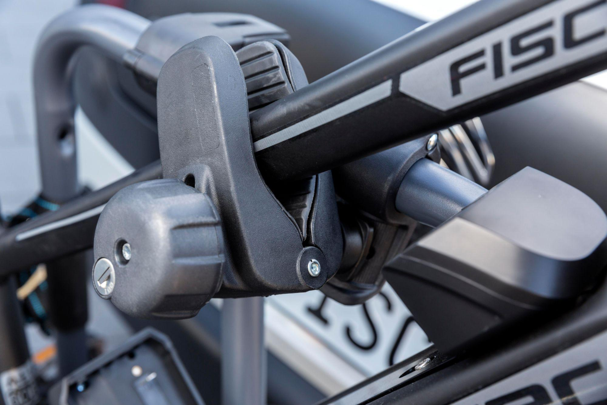 Nahaufnahme eines schwarzen Fahrradträgermechanismus. Der Träger hat einen Verriegelungsmechanismus, mit dem Namen FISCHER in Grau.