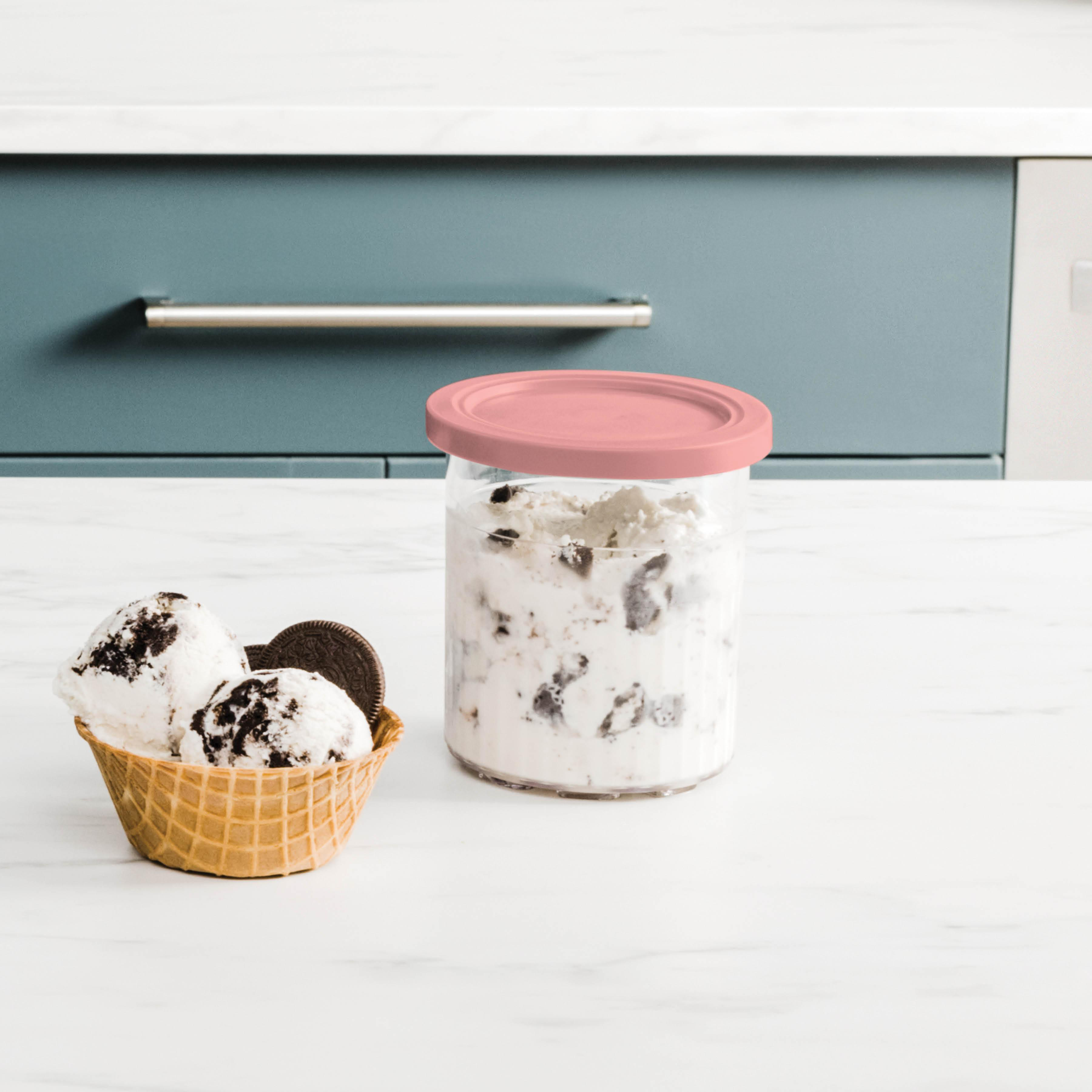 Eis in einem Waffelbecher und einem Glas. Beide enthalten Cookies-and-Cream-Eis. Ein rosa Deckel bedeckt das Glas.