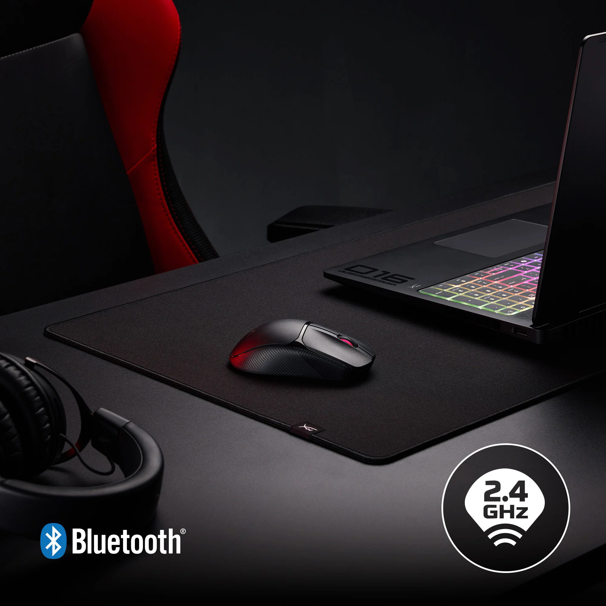 Konfiguracja do gier z laptopem, myszką i słuchawkami na czarnym biurku. Czerwono-czarne krzesło w tle.