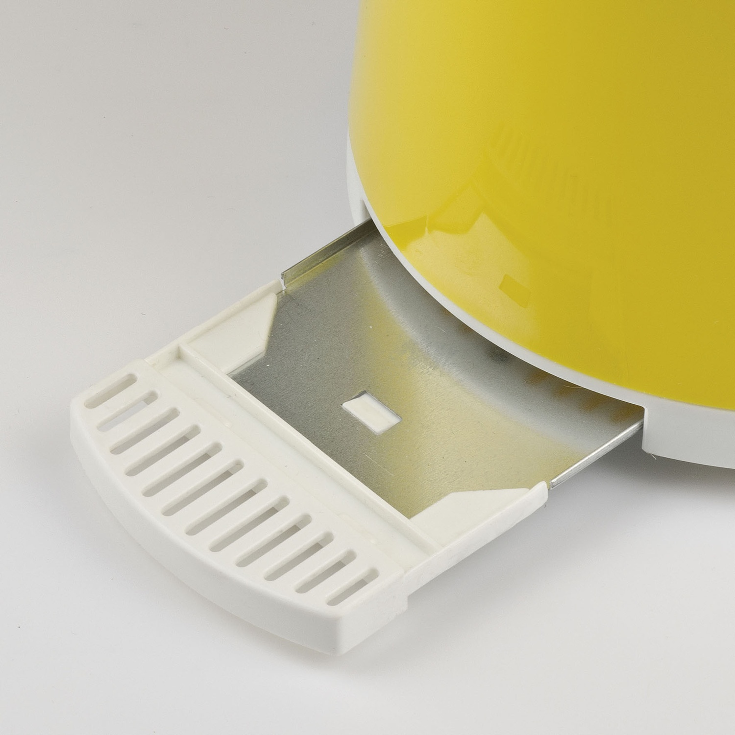 Primo piano di un tostapane giallo e bianco. Il vassoio raccoglibriciole è estratto. Lo sfondo è bianco.