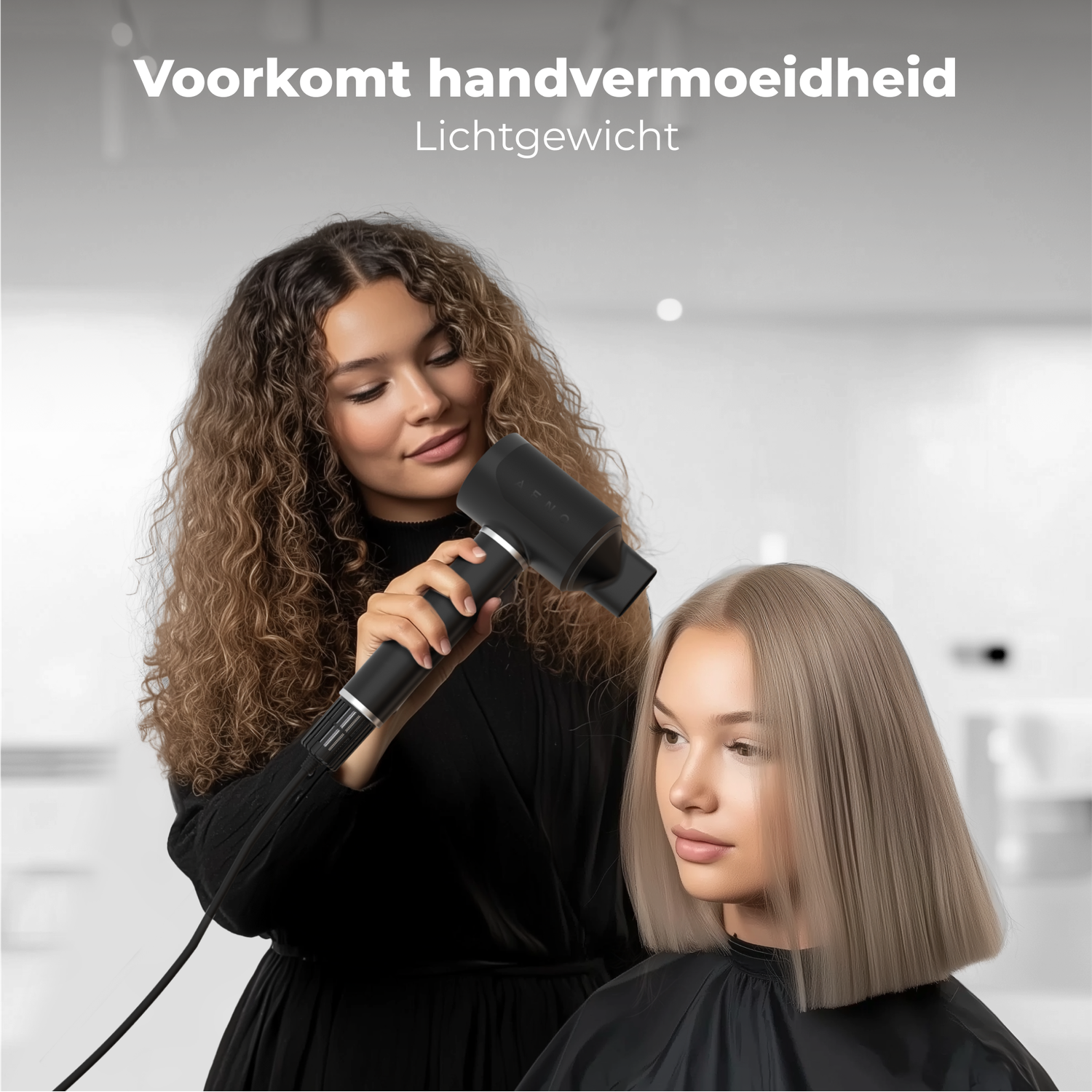 A woman using a black hairdryer on another woman's blonde hair. Both women are in a salon setting. Hairdryer is in action.