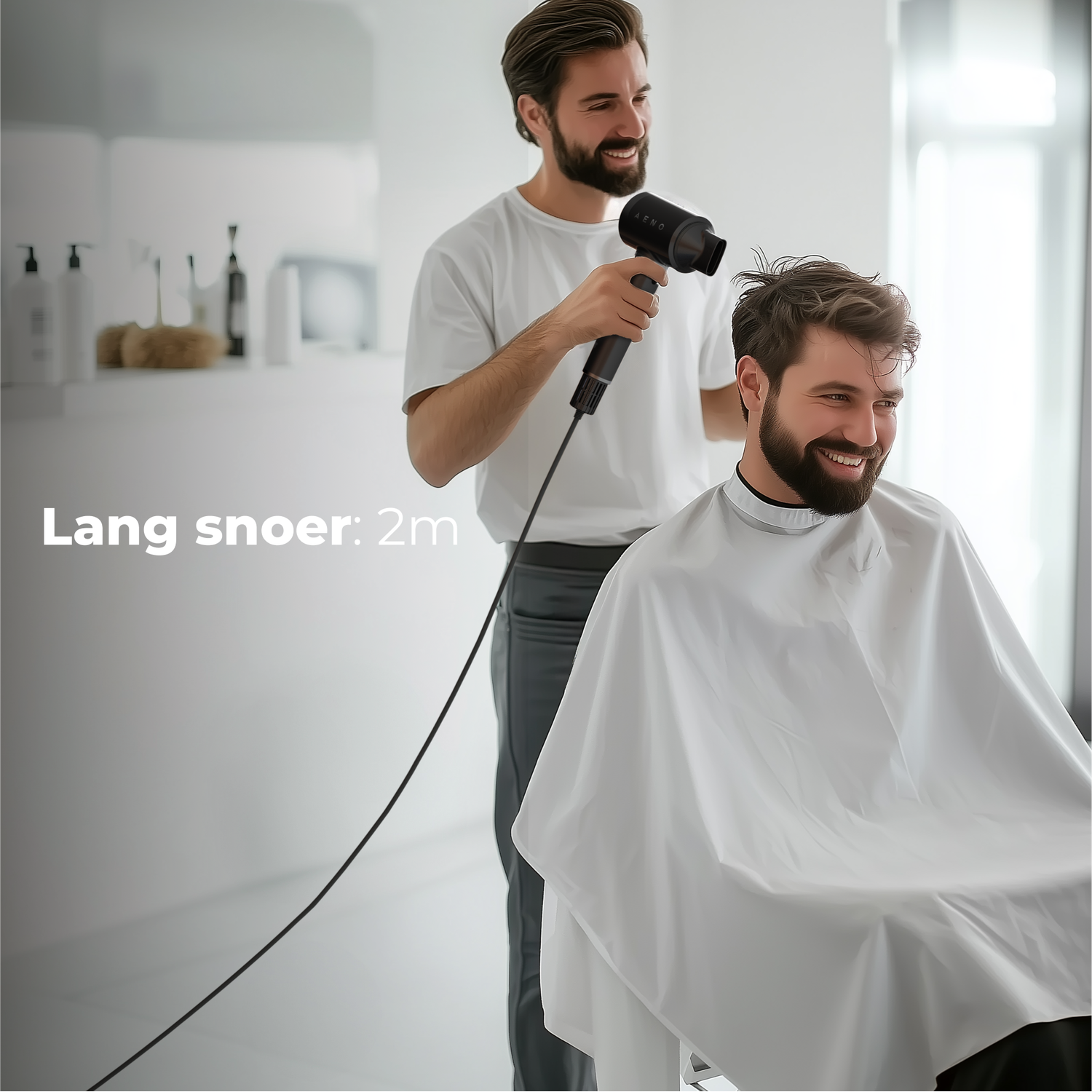A barber drying a customer's hair with a black hairdryer. Both men are smiling. The customer wears a white cape.