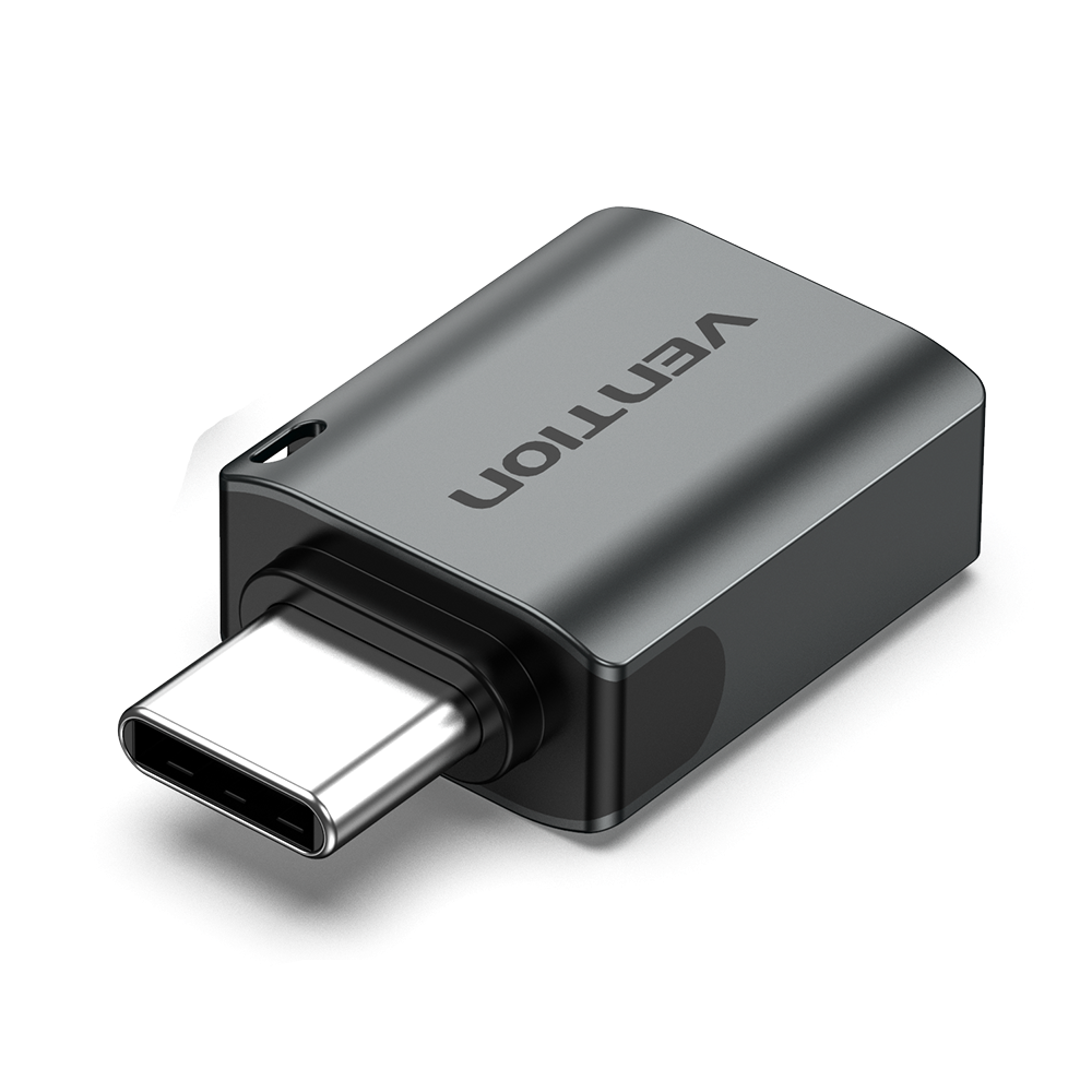Egy USB-C adapter. A test szürke, a Vention márkanévvel. Egy ezüst USB-C csatlakozó alul. Fekete háttér.
