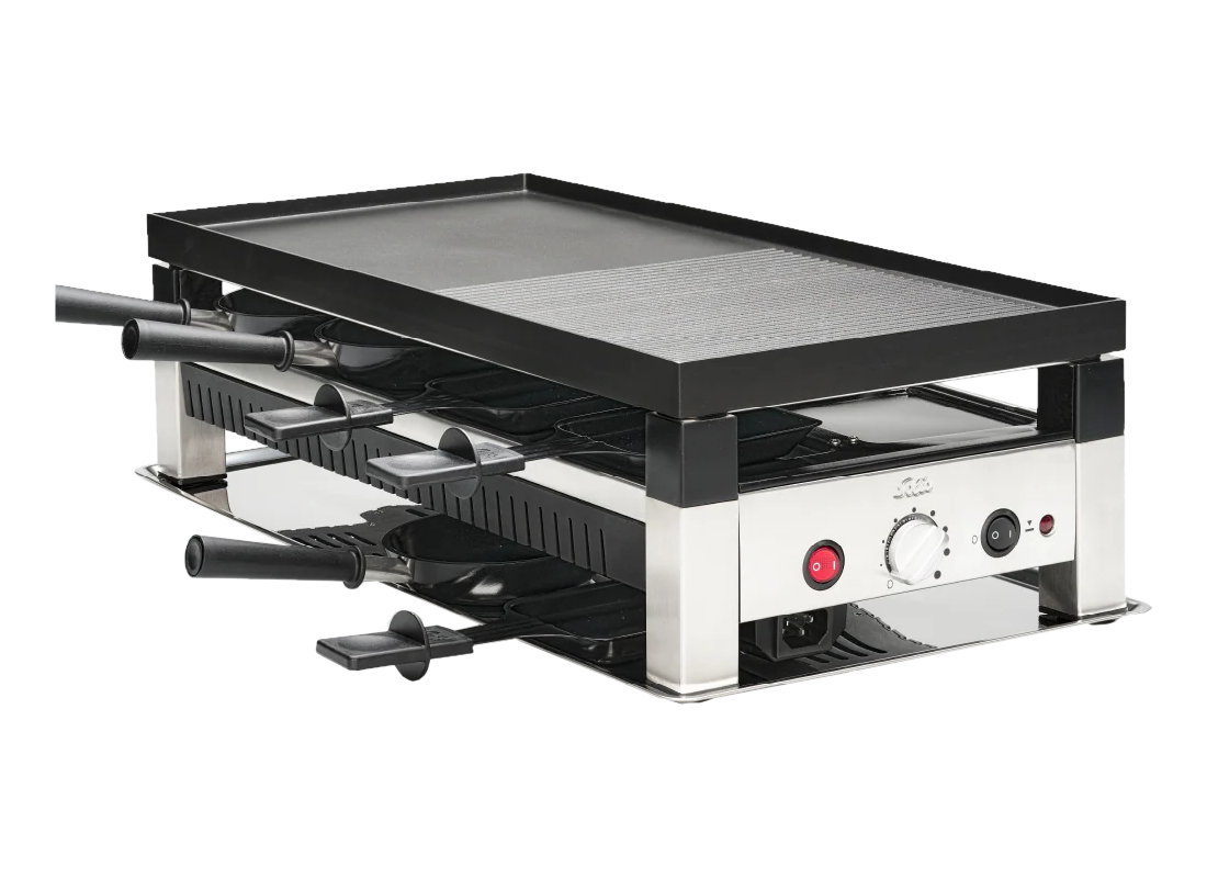 Raclette-Grill mit schwarzer Grillplatte und Pfannen. Silberner Rahmen mit schwarzen Griffen und Bedienfeld. Isoliert auf Schwarz.
